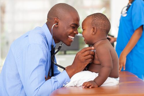 Male doctor listening to a baby boy's heart with a stethoscope